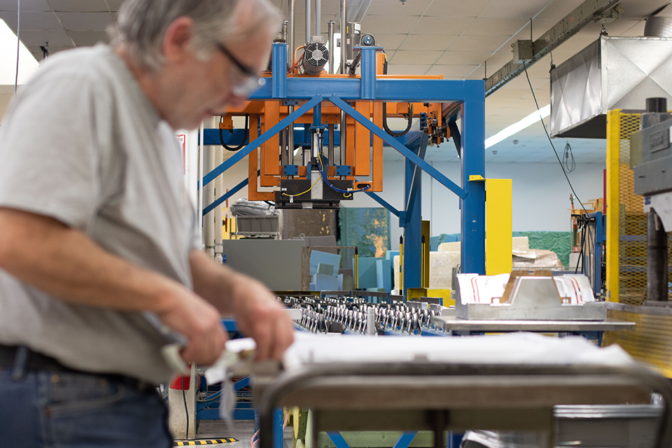 A man working on a compression molding machine in medical device manufacturing industry. 