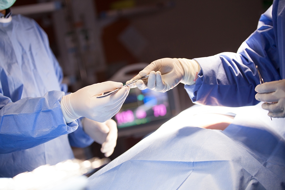 A photo of surgeons exchanging a surgical instrument.