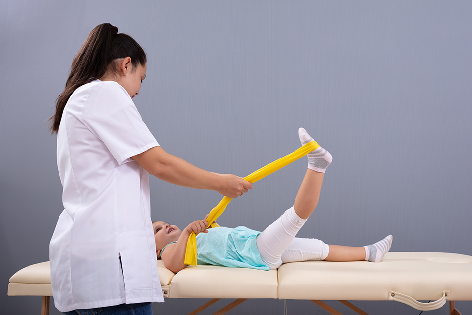 A photo of a doctor using a band to position a child's leg.