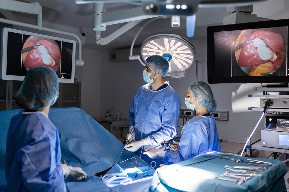 A photo of surgeons performing an endoscopic surgery while looking at monitors.